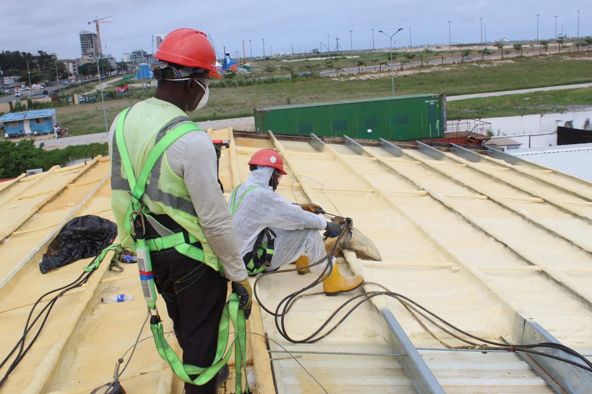Team spraying polyurethane foam insulation on an industrial roof