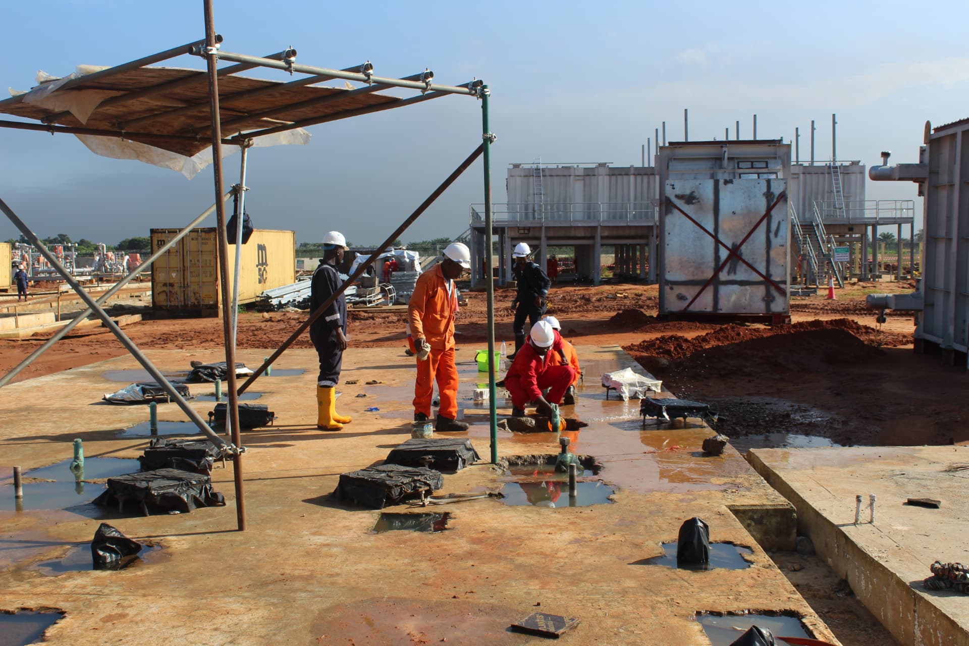 Technicians working under shade scaffolding on foundation grouting pockets