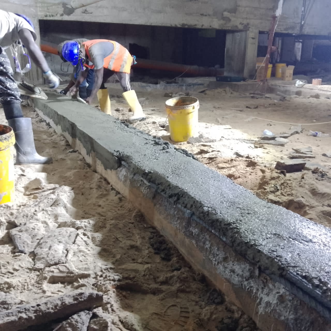Crew trowelling repair mortar onto the basement beam soffit
