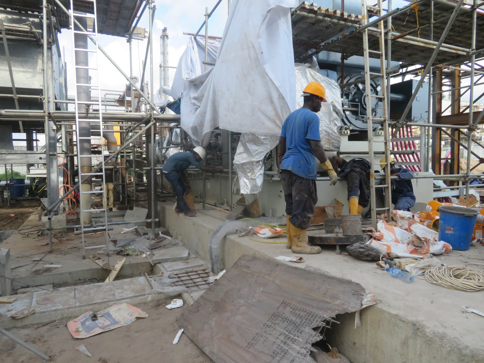 Crew placing non-shrink grout under a machine base plate