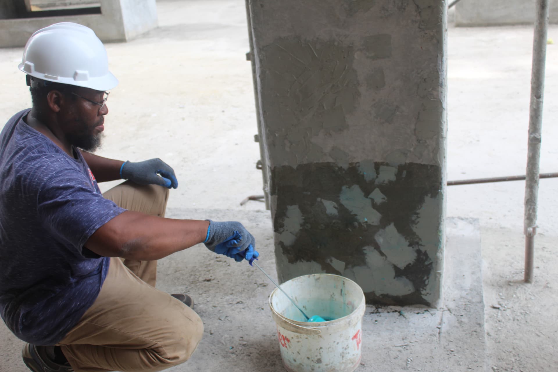Engineer mixing epoxy primer beside a prepared concrete column