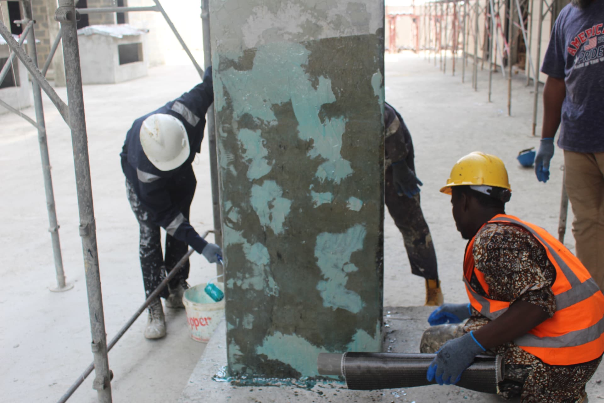 Crew priming a column while a technician unrolls carbon fibre fabric
