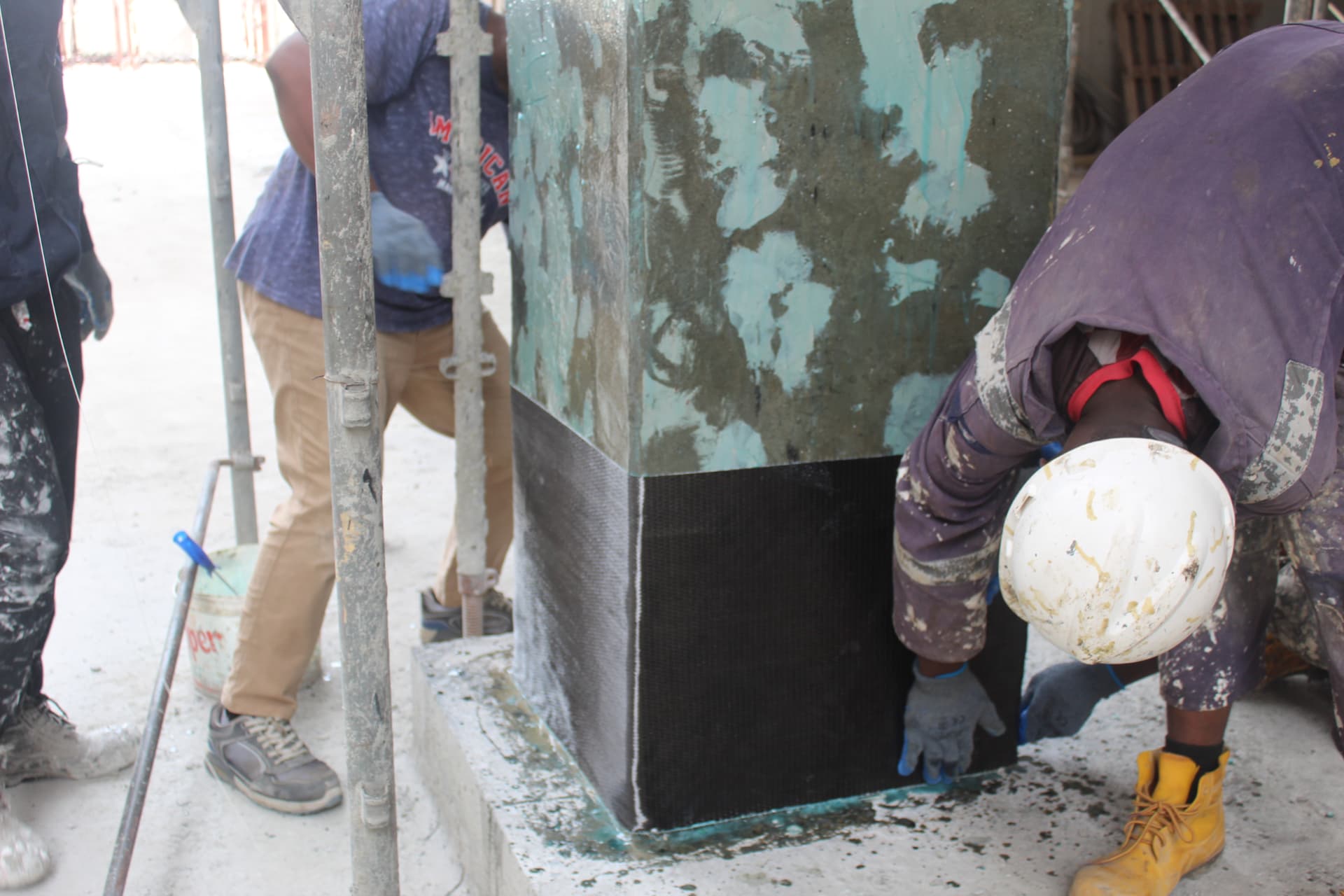 Operatives wrapping carbon fibre fabric around the base of a column