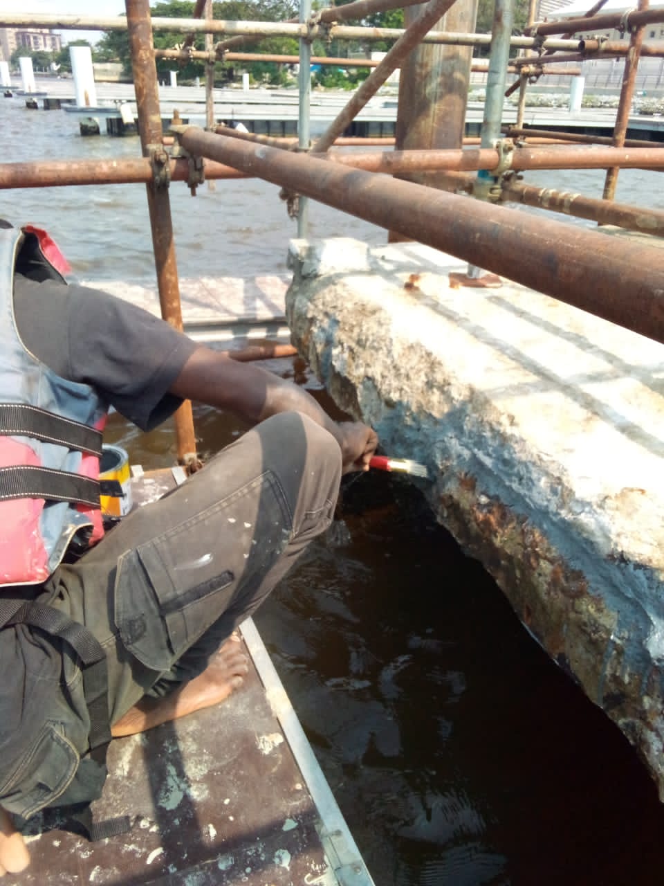 Operative coating the repaired jetty beam from a working platform