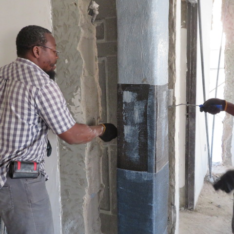 Crew applying epoxy and wrapping carbon fabric around a concrete column