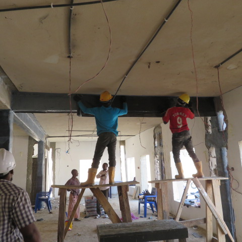 Team installing carbon fabric to a beam from working platforms