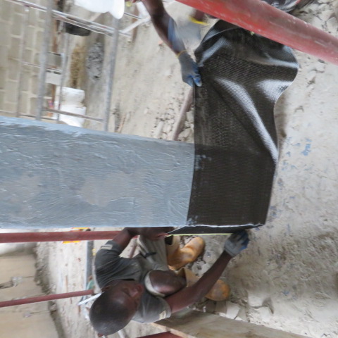 Two operatives stretching carbon fabric around a column base