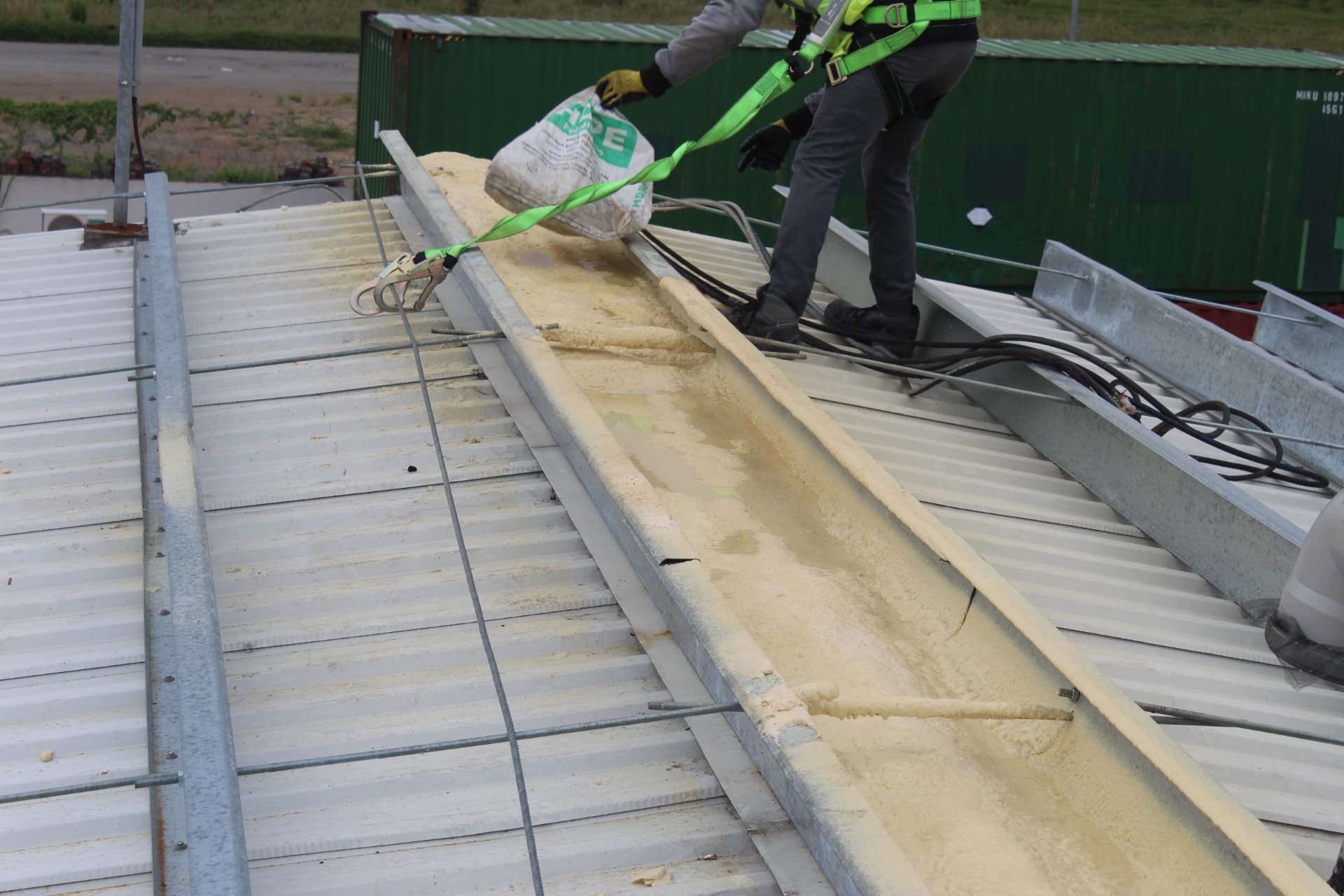 Operative placing material along a freshly foamed roof valley