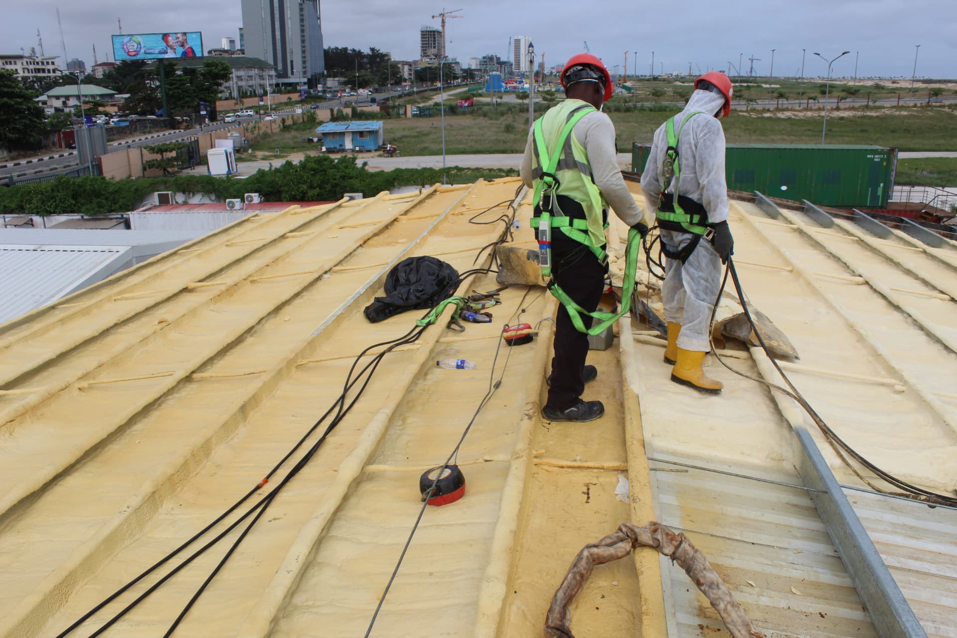 Two-man spray team moving along the insulated roof slope