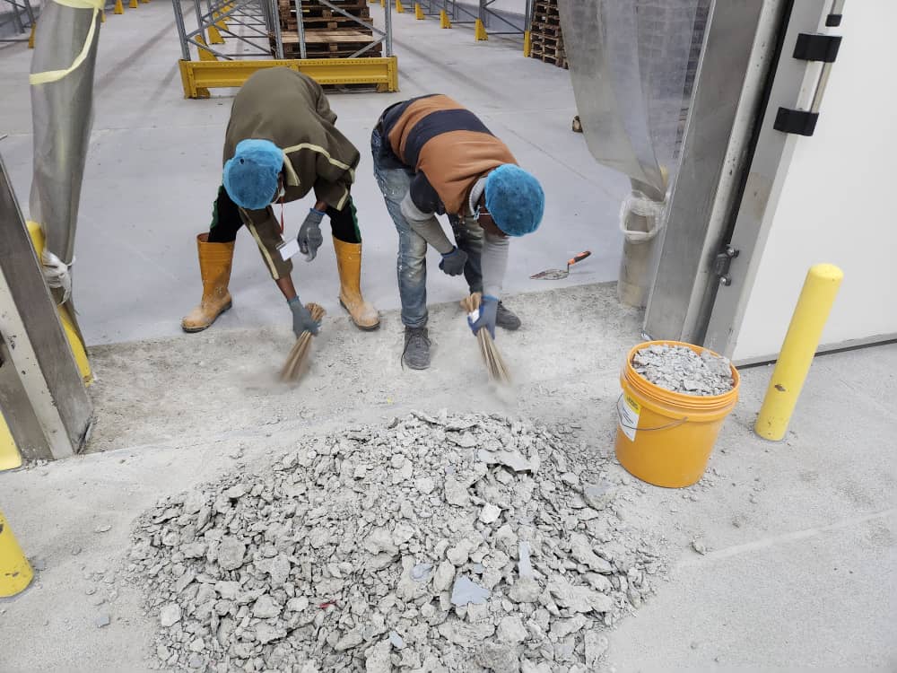 Crew sweeping out concrete debris at the cold room doorway